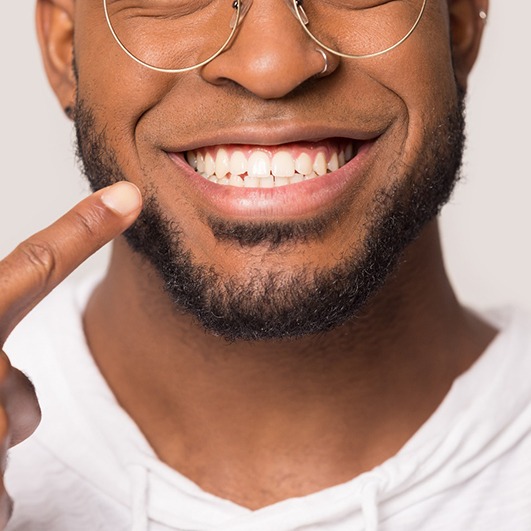 smiling man pointing to his smile after cosmetic dentistry in Brick Township