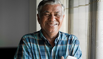 older man smiling by a window