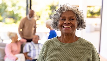 older woman smiling with friends in the background
