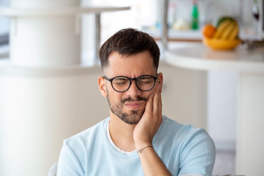 A man holding his face due to gum pain.